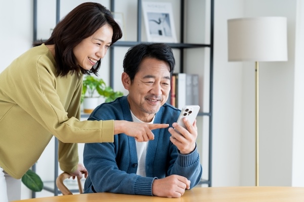夫婦がスマホ画面を見て笑顔